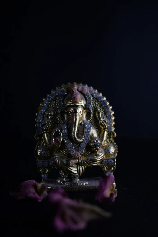 an ornate statue with beads and some pink flowers