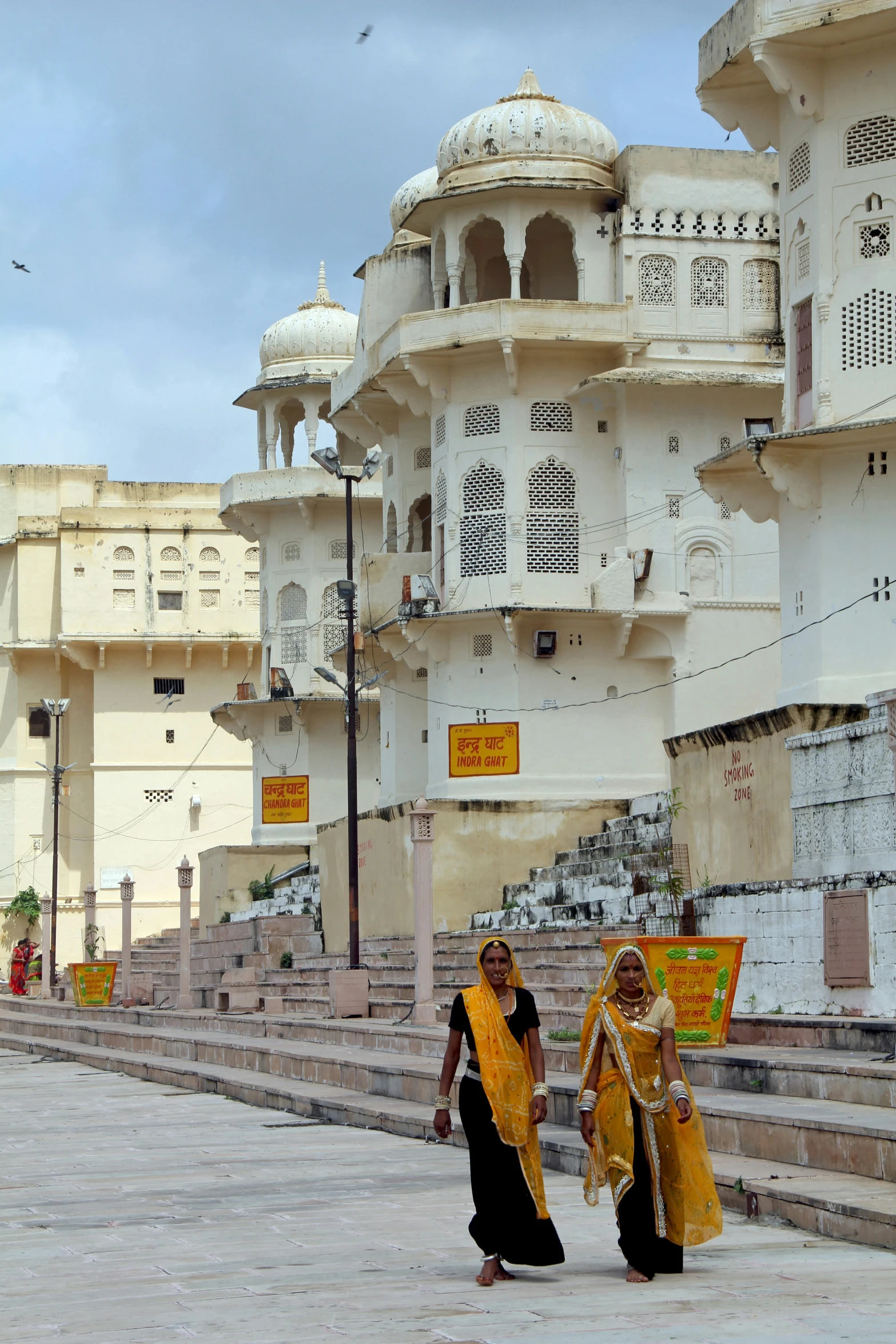 two women walking in a walkway by some buildings