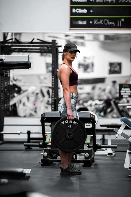 a woman with a cap and tights holds a barbell