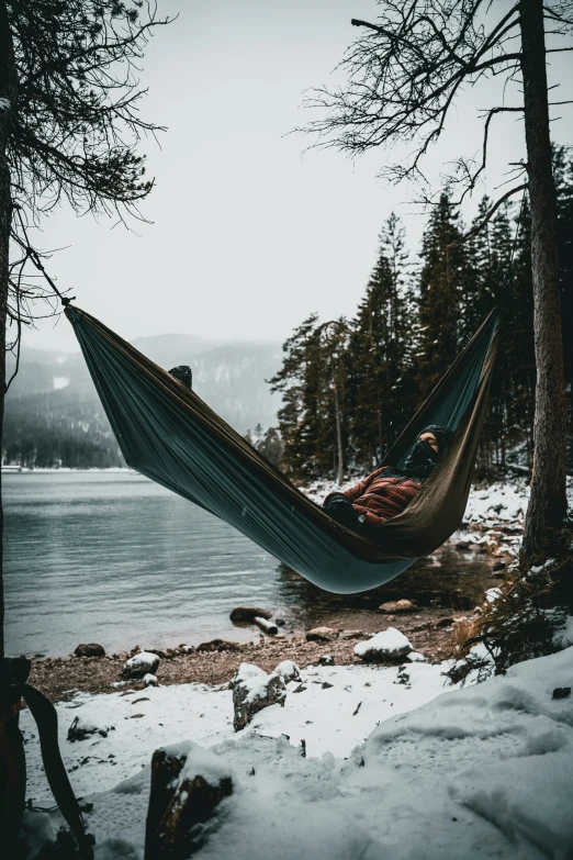 the man sits in a hammock at the waters edge