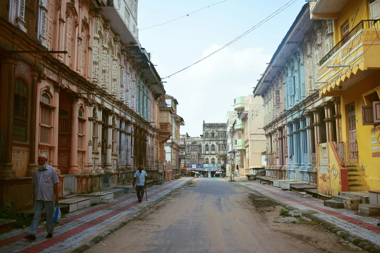 people walk down an empty street in front of buildings