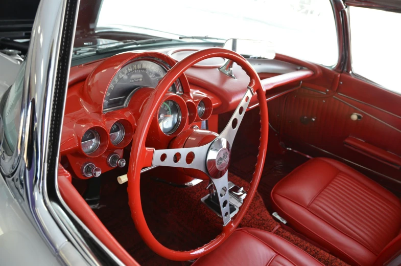 a red dashboard and steering wheel sitting next to a white car