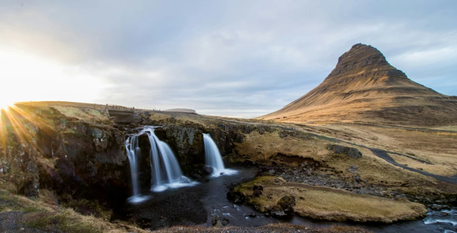 waterfall with sun shining through it on a mountainous slope