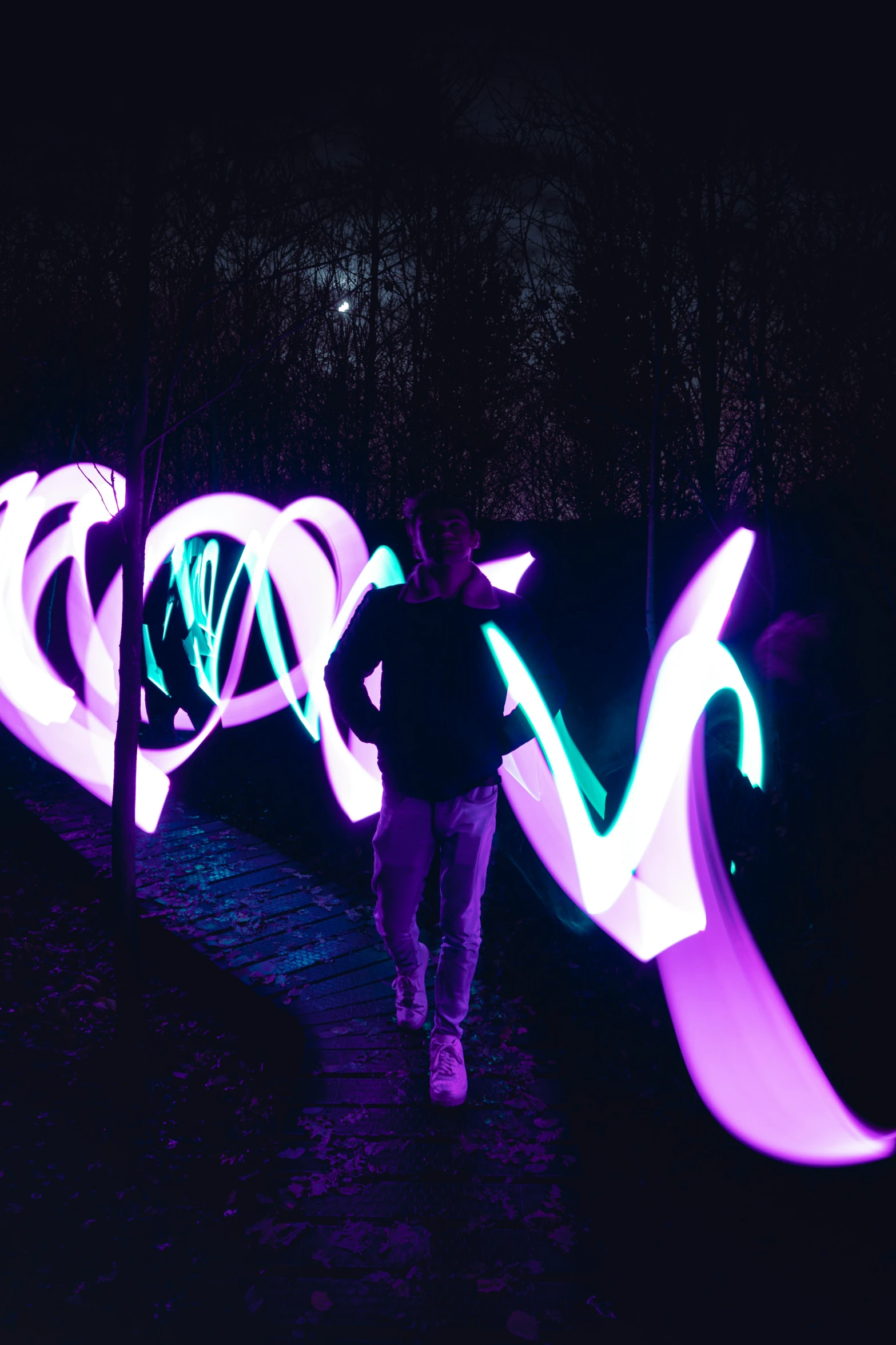 purple light pograph on black background of a person walking down a path