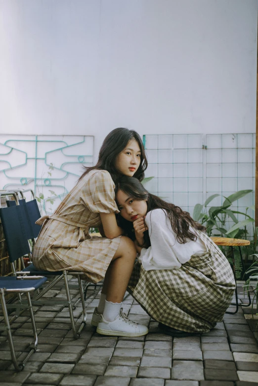 two girls sitting on benches with hand bags