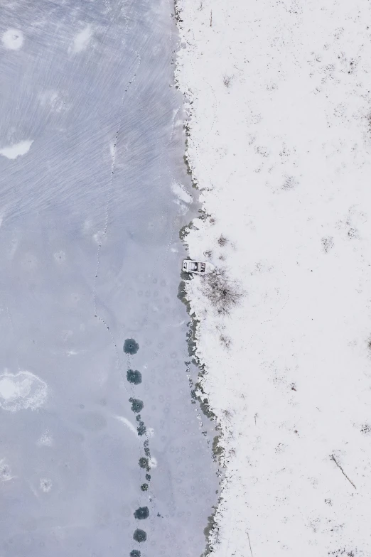 a footprints imprint in the snow next to a frozen body of water