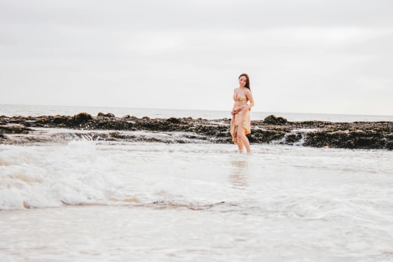 a beautiful woman standing in the water near a shore