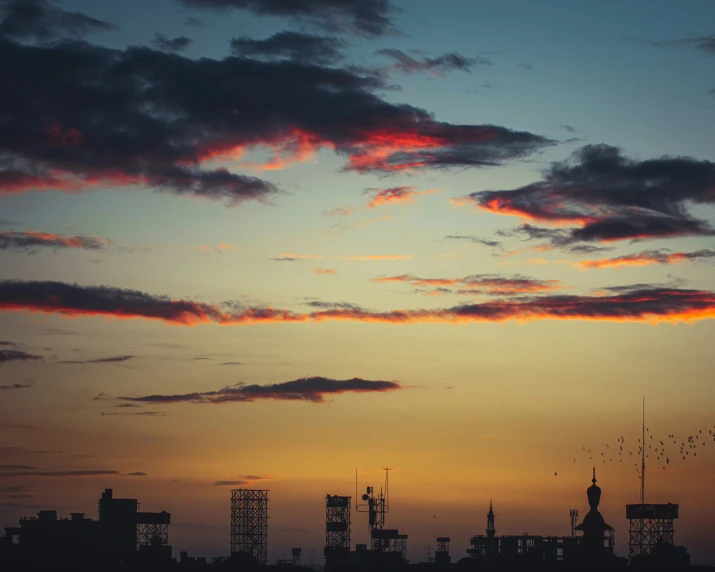 the silhouette of a city with clouds at sunset