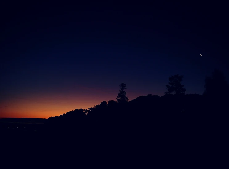 a silhouetted hill in the distance at sunset