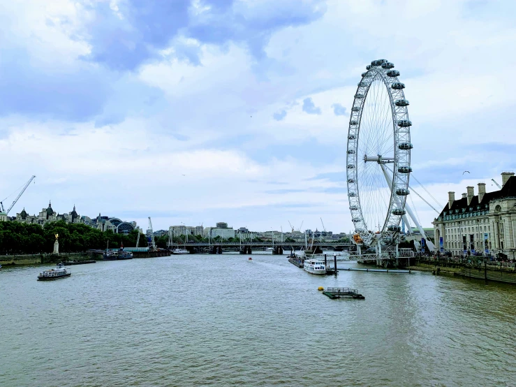 an artificial ferris wheel sits over a river in a city