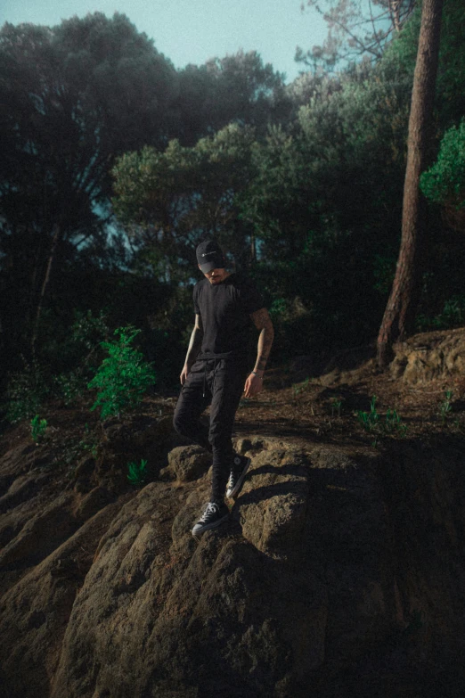 a man in black outfit walking through a rocky area