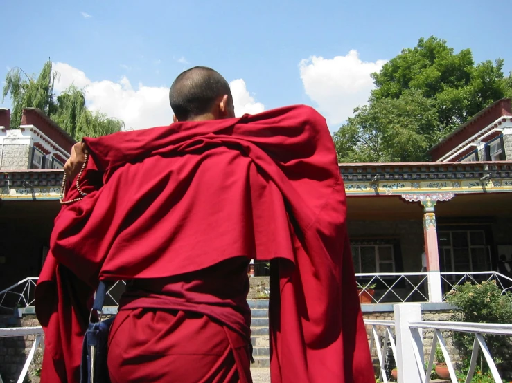 a man wearing a red robe walking away from his home