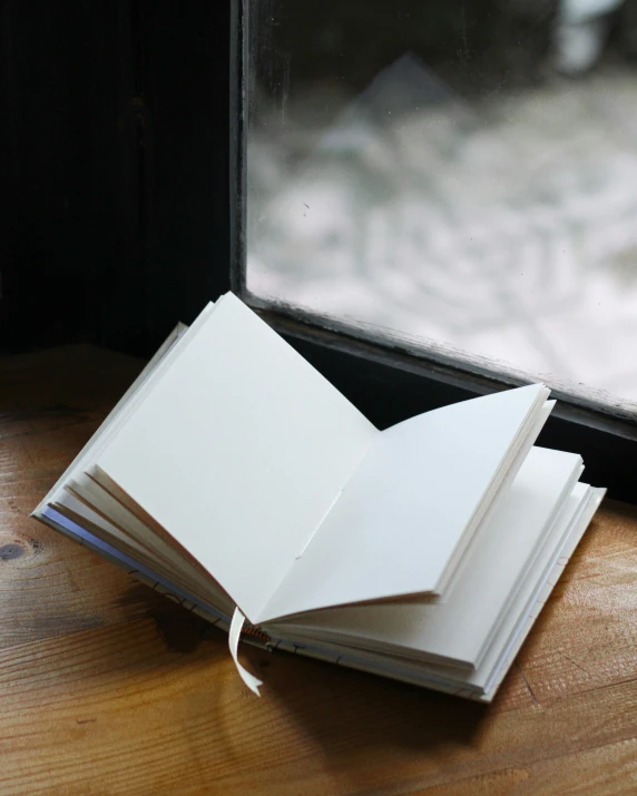 a stack of books sits next to an open window