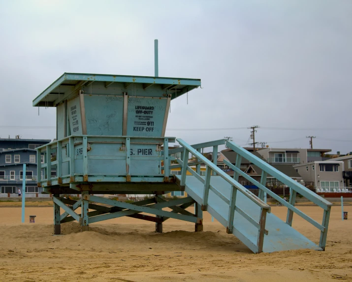 a lifeguard tower stands on a beach next to an apartment complex