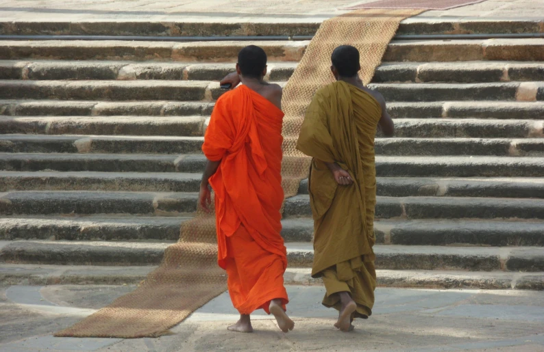 two young men in orange robes walking next to steps