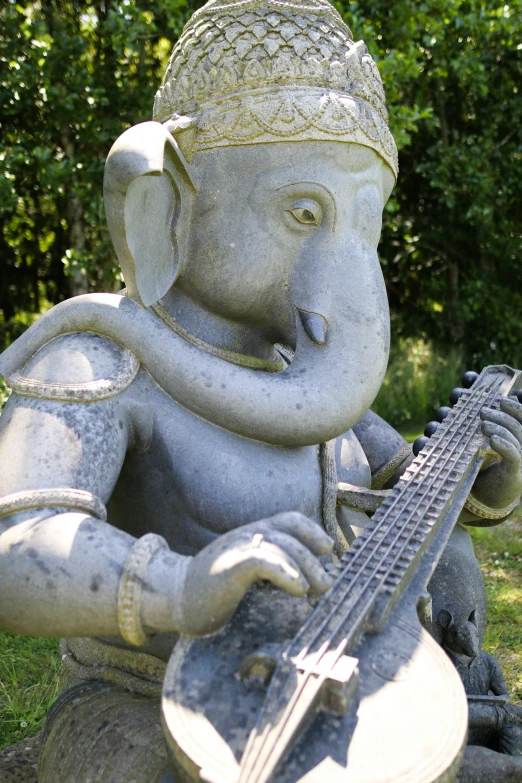 a small elephant statue holding a guitar in its trunk