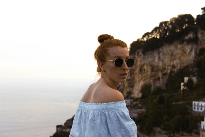 a woman wearing sunglasses next to a cliff
