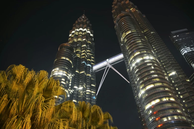 two tall towers lit up at night under the lights of skyscrs