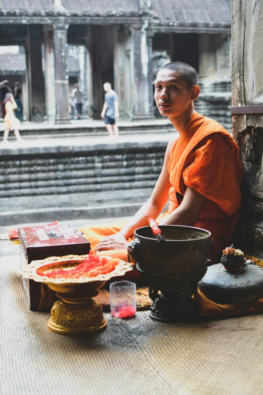 an asian monk seated next to a bowl of food