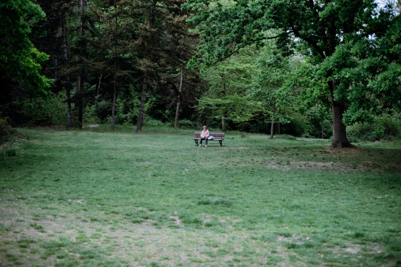 two people sitting on park benches in the middle of a field