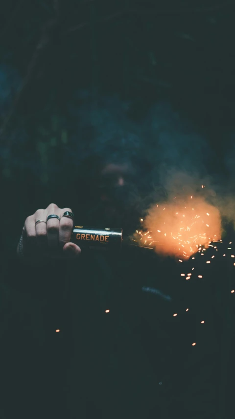a hand holding up a lit cigarette with lots of sparks