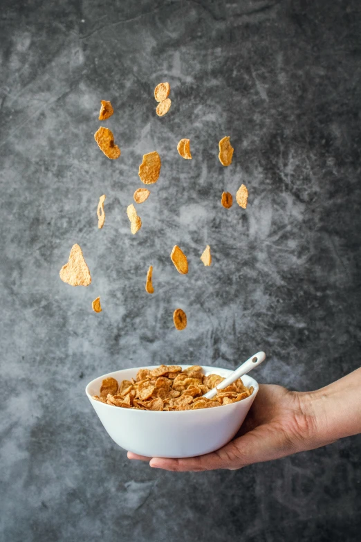 a hand holding a bowl full of cereal