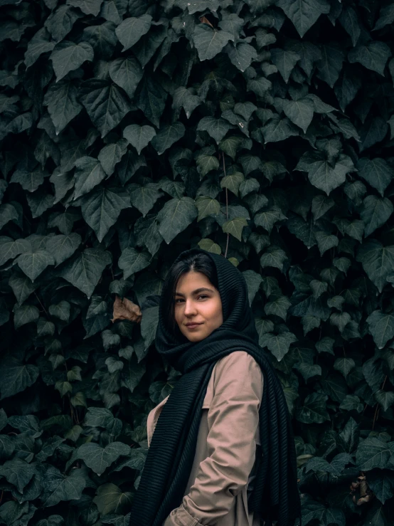 a woman with black shawl standing by vines