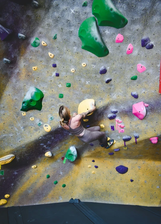 a woman is on top of a climbing wall