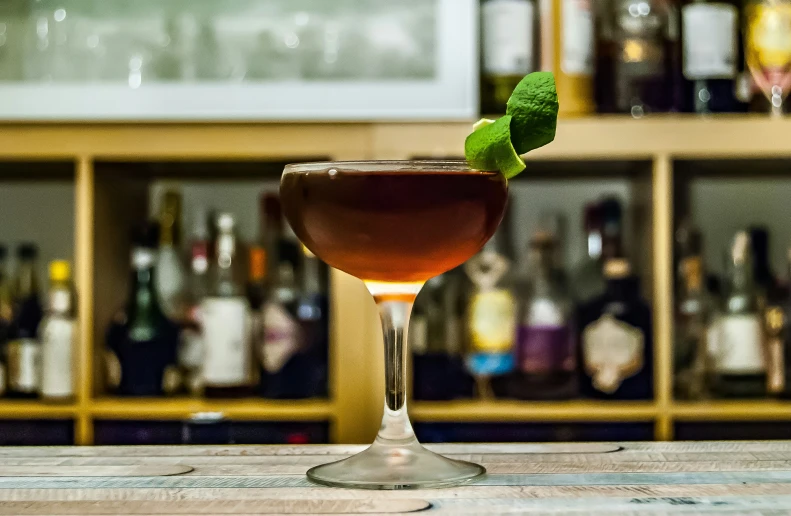 a cocktail sits in front of liquor bottles