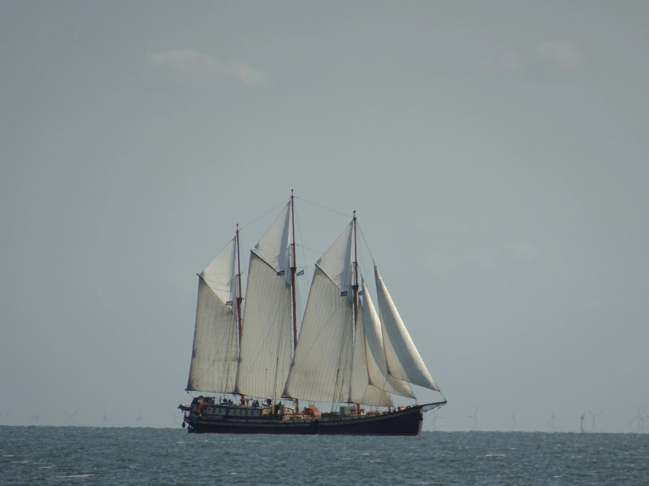 a sailboat with many sails sailing through the ocean