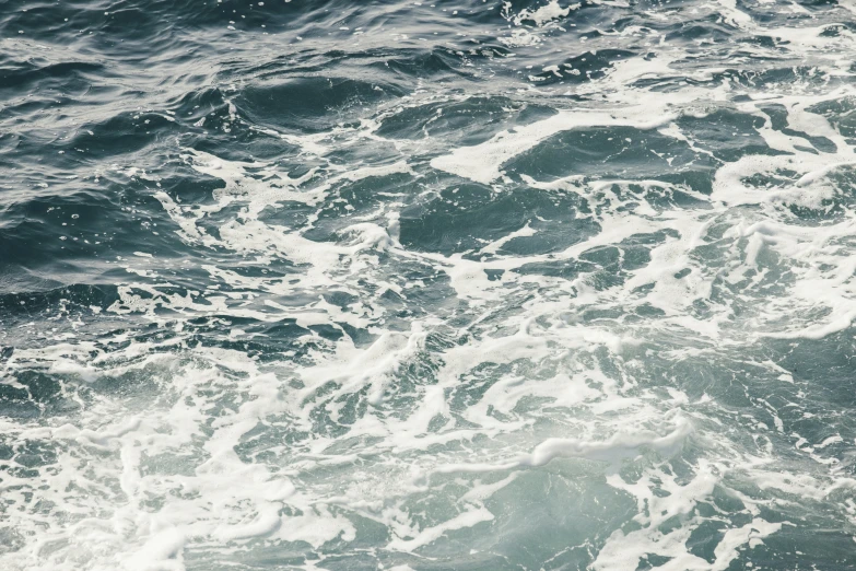 two seagulls flying over the ocean in high water