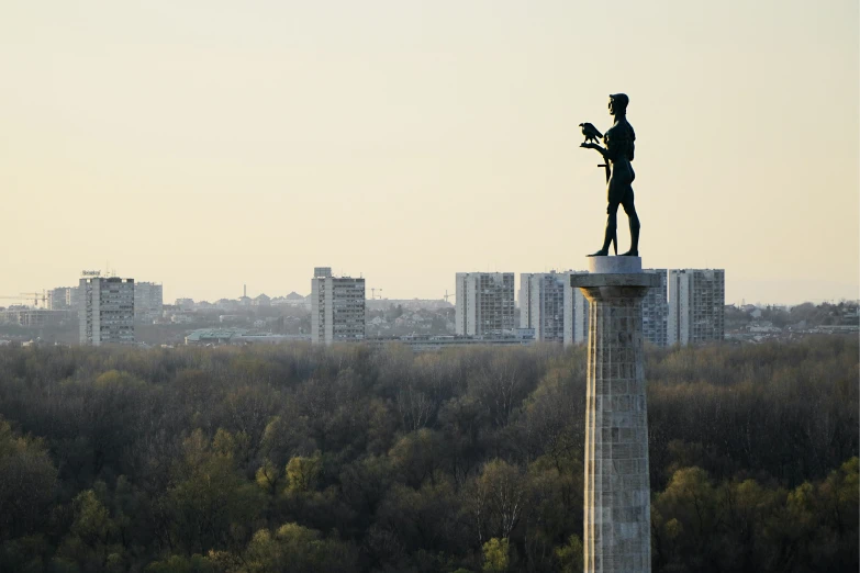 a statue on top of a pedestal surrounded by trees