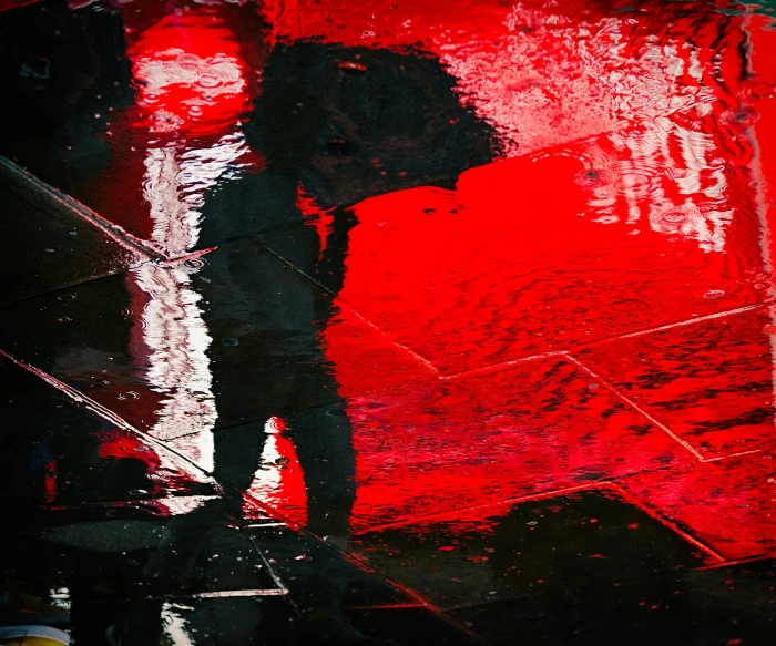 a person walking past a red wall with a big umbrella