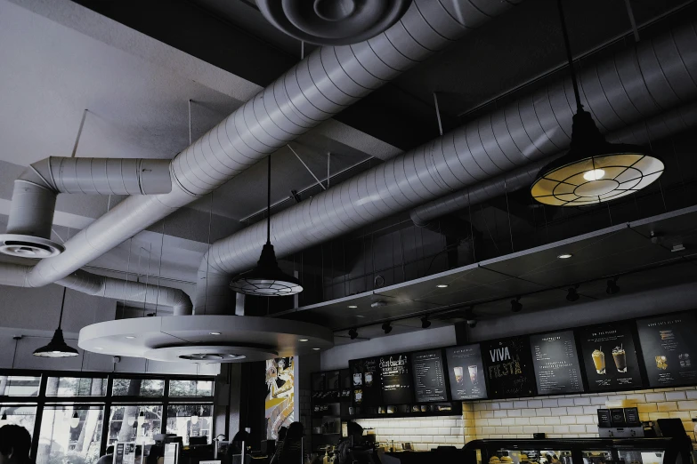 a restaurant filled with tables and hanging lights