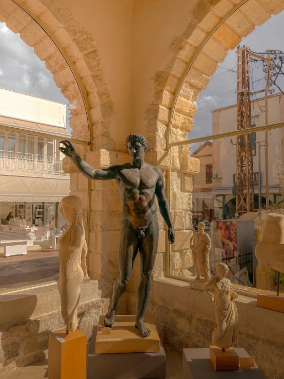 three statues stand in front of a sculpture of a man holding his arm out