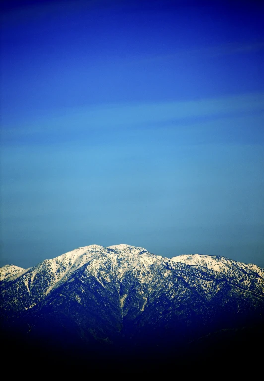 snow capped mountains against blue sky in the distance