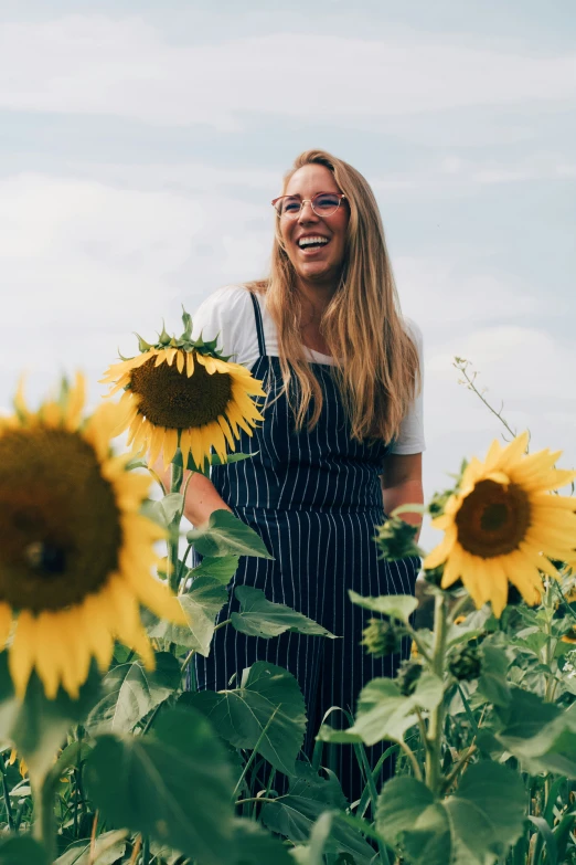 a woman is smiling while standing in a field full of sunflowers