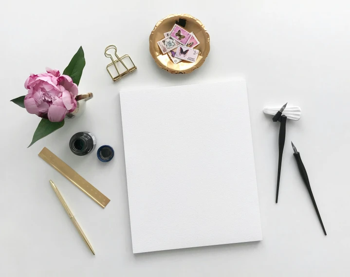 a notepad, pen, sticky pad and other items laid out on top of a white surface