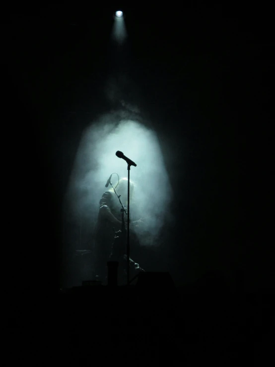 a concert stage with a microphone and a person in the dark