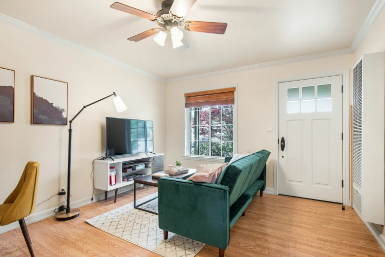 a living room with wooden floors and green couch