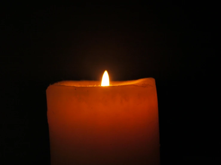 a single lit candle in the dark