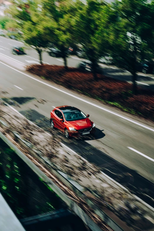 a red car driving down the middle of the road