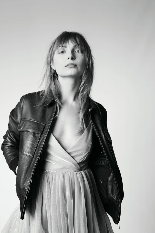 a woman wearing a leather jacket and white dress