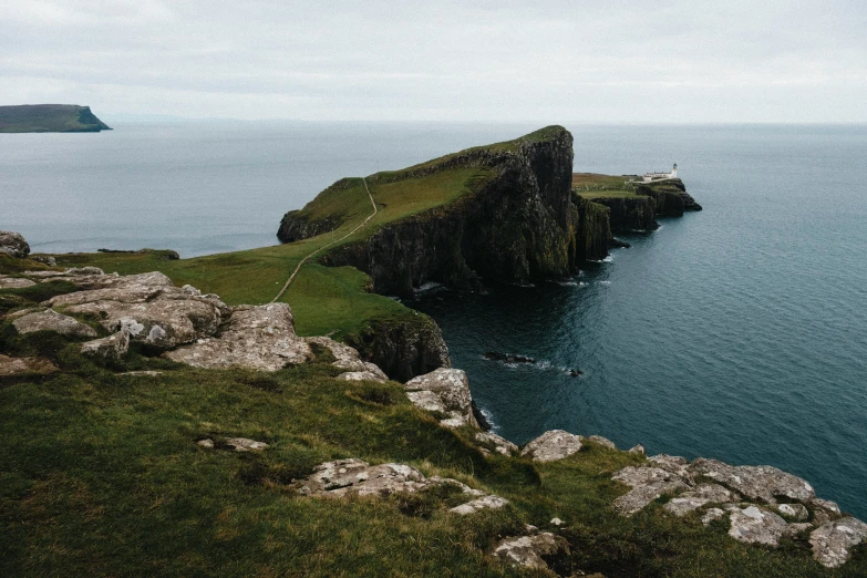 a long dark cliff overlooking the water on a cloudy day