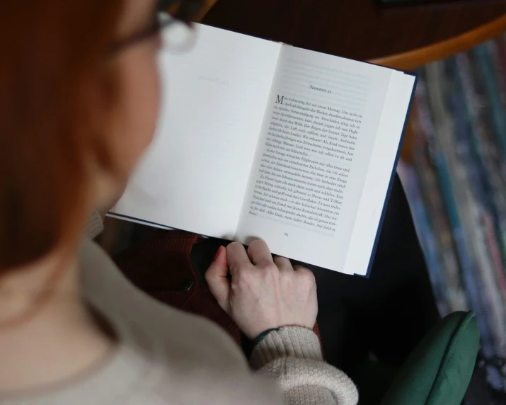 a woman holds a book open to reveal an image of a poem