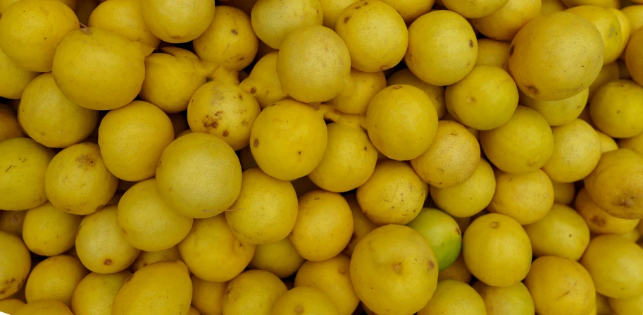 a pile of yellow apples and lemons with the top down