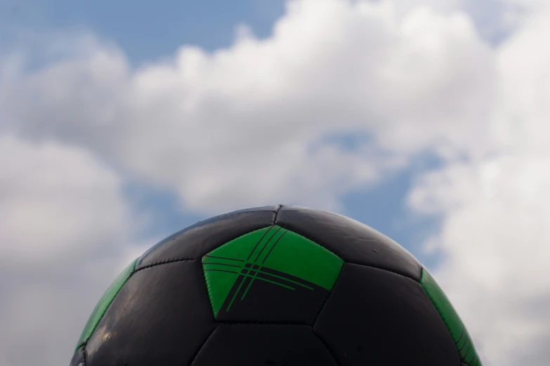 the black and green ball with an arrow on it is in the foreground against the blue sky