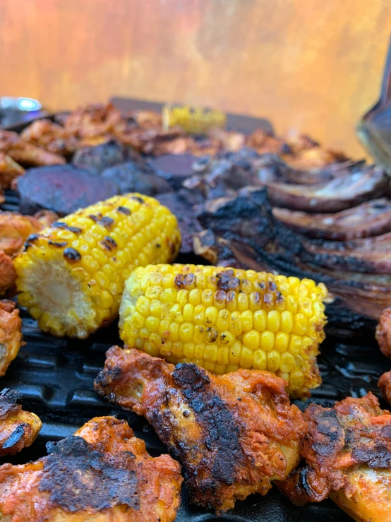 a barbecue grill with pieces of cooked meat and corn on the cob