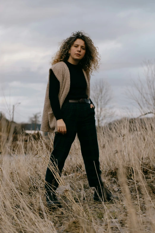 a woman standing in tall grass with long hair