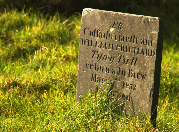 an old granite headstone in the grass